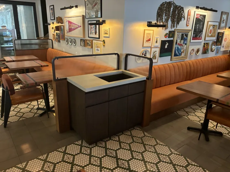 Channel-backed banquette seating, dining tables, and a service cabinet at Birdie G's.