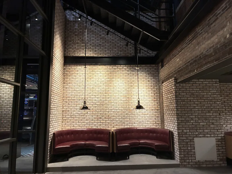 A wider view of curved booths, brickwork, and an open staircase.