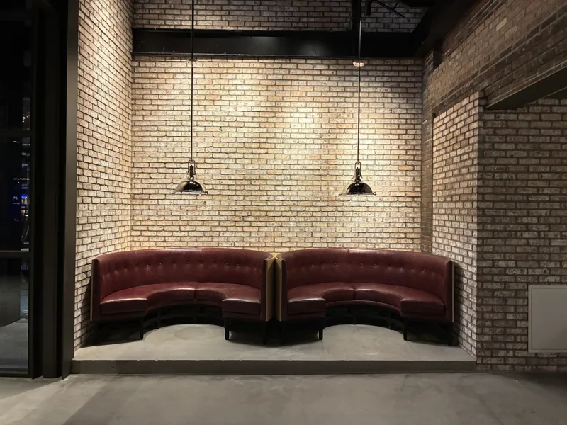 Two curved burgundy booths set against a brick wall.