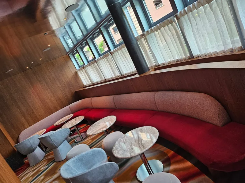 Curved banquette seating, lounge chairs, and round tables in a wood-paneled interior.