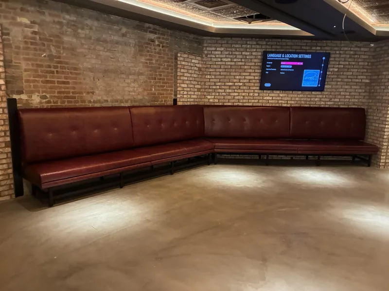 A long corner banquette with burgundy upholstery in an open interior.