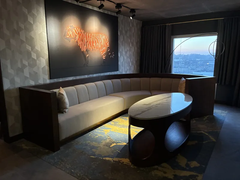 Upholstered corner seating and an oval table beside a window.