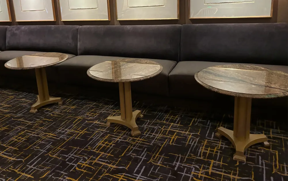 QBC upholstered banquette seating with marble-top tables